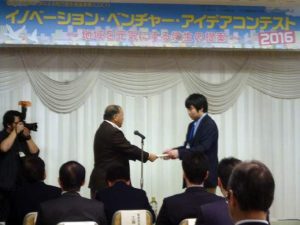 写真2 準グランプリの賞を受け取る若沢さん。 プレゼンターは丹羽八戸学院大学副学長。